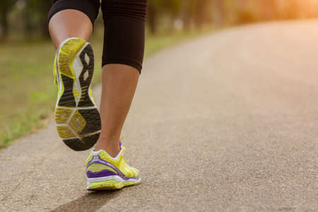 close up sport woman running in park during sunsetの写真素材