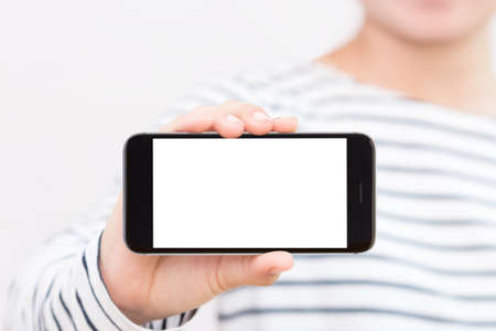 woman holding phone white screen selective focus on hand showingの写真素材