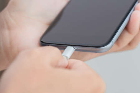 close up hand using usb cable connect to phoneの写真素材