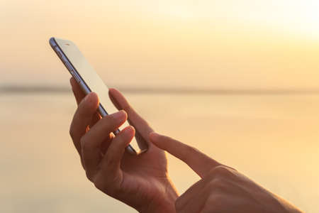 closeup hand using phone during at sunsetの写真素材