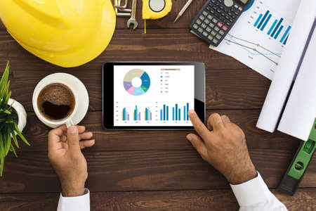 engineer using tablet checking business graph on work table