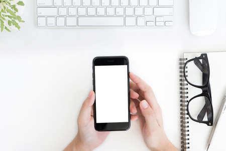 close up woman hand hold phone blank screen on white tableの写真素材