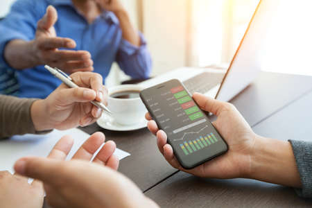 meeting business people team and showing graph screen on phone mobile in office roomの写真素材