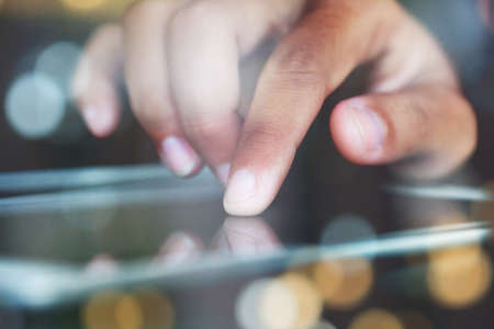 close-up finger touching on communicator electronic device on nightの写真素材