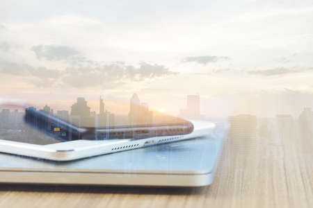 communication device stack on desk and city background reflect modern technology conceptの写真素材