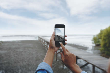 selective focus on hand using smart phone taking landscape photoの写真素材