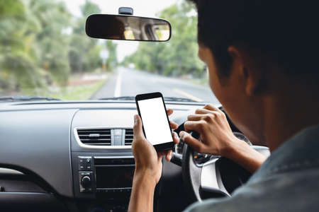 man looking at phone inside carの写真素材