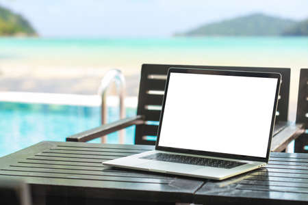 laptop computer showing blank screen on table beauty beach backgroundの写真素材