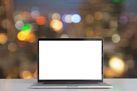 laptop showing blank screen on desk see through lights in city on nightの写真素材