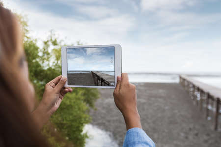 Woman use digital tablet taking landscape photoの写真素材