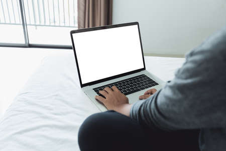 woman typing laptop keyboard showing white screen on bed inside roomの写真素材