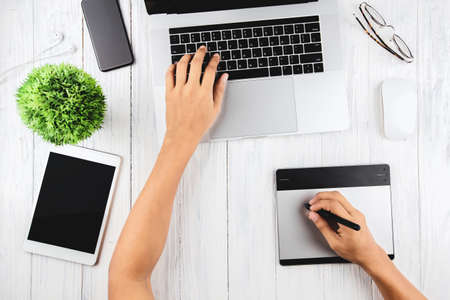 graphic designer using laptop and graphic tablet on top view
