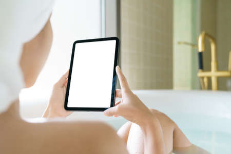 Using digital tablet, Women holding digital tablet while soaking in the bathtub in moringの写真素材