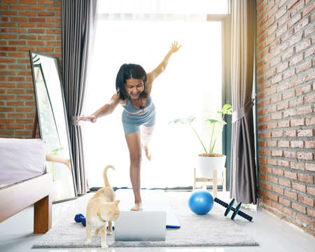 woman trying to exercise and looking at her laptopの写真素材