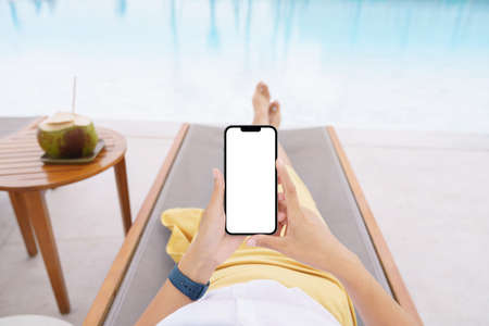 woman lie down on pool bed using phone white screenの写真素材