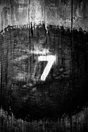 seven is large on a wooden post in black and whiteの写真素材
