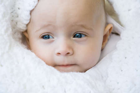 baby boy wrapped in a white blanketの写真素材