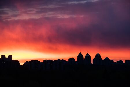 colorful fiery sky at sundown with cirrus clouds above city skylineの写真素材