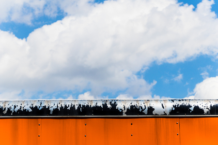 Clouds and blue sky behind orange and black metalの写真素材