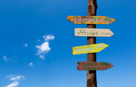 Colorful wooden signs with distances to other cities against a blue skyの写真素材