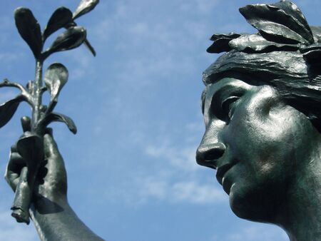 Statue of a goddess holding an olive branch against a clear blue sky, in Montreal, Quebec, Canada.の写真素材