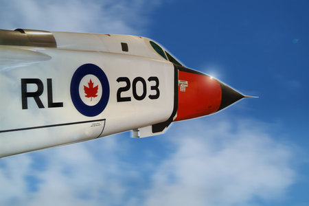 A white Canadian jet interceptor glints in the sun as it breaks out of the clouds, at the speed of sound, and into a clear blue sky.の写真素材