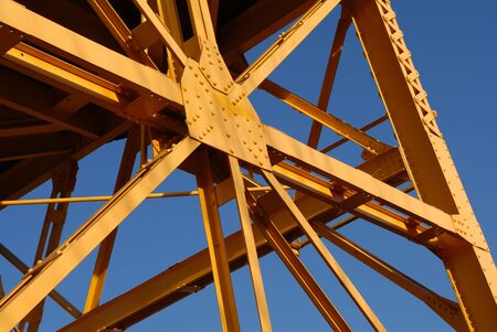 A detail of an old yellow freight crane against a bright blue sky.の写真素材