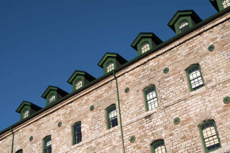 Seven green attic windows atop an old stone industrial building.の写真素材