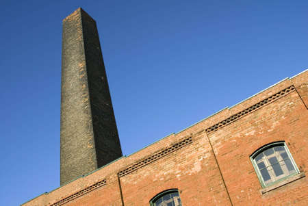 A disused smokestack towers above an old industrial building.の写真素材