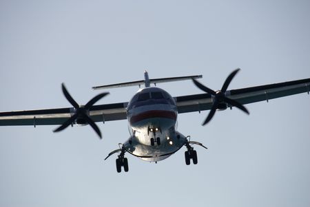 A twin-engined turboprop passenger plane landing at dusk.