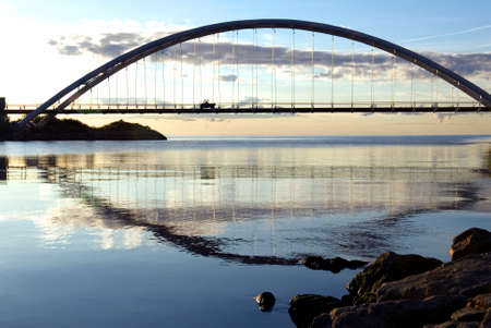 An electric vehicle crossing a suspension bridge near Lake Ontario, just after dawn.の写真素材