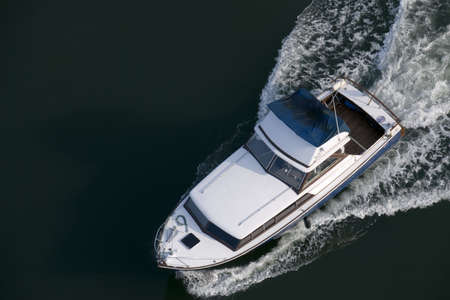 A blue and white cabin cruiser, with a wet canopy, shot from above while leaving harbour.の写真素材