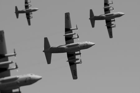 A fleet of USAF Lockheed C-130 Hercules transport planes flying overhead. (Shot with minimum depth...
