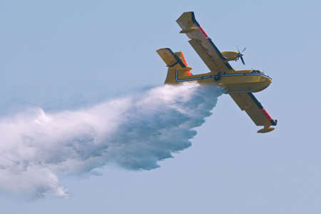 A twin-engined  bomber dumping its load on a forest fire.