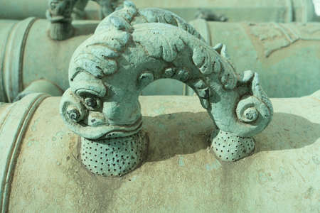 Two stylized bronze dolphin cannon handles, shot with minimal depth of field.