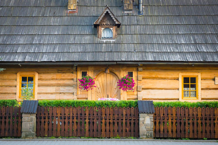 Wooden highlander house covered with shingle. Entrance door, flowers hanging at the entrance.の写真素材