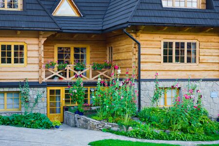 Wooden highlander's house. Plants and flowers in front of the house.の写真素材