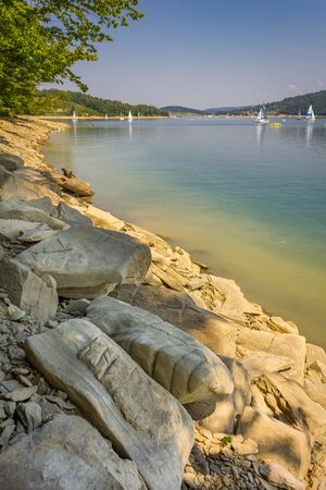 Bieszczady Mountains, Poland. Solina Lake. View of the lagoon, sailboats in the distance. Rocks on the shore of the lake.の写真素材