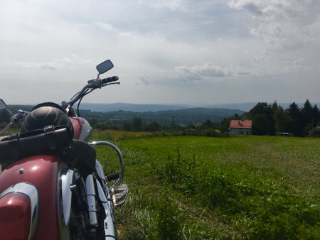 A motorcycle with a helmet on the seat in the distance, a vast view of the hillsの写真素材