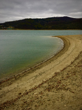 Dirt road on the shore of a lake in the mountains.の写真素材