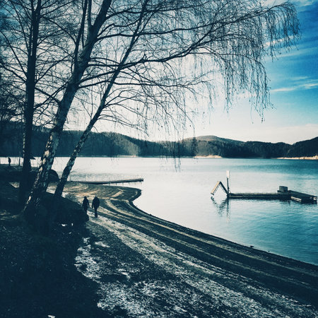 Vintage photo of winter landscape with lake, trees and blue sky