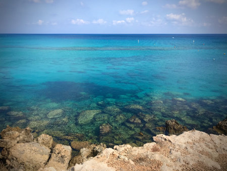 Rocky sea shore, clear sea water, beautiful blue color visible at the bottomの写真素材