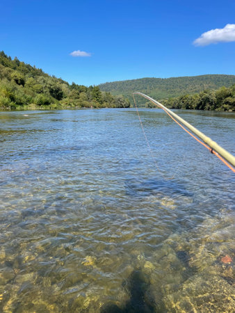 View of clear water in a mountain river, visible fly rod.