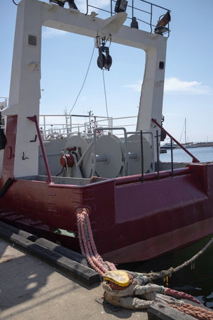 A large red boat with a white top is docked at a pier. The boat is tied to a dock with a ropeの写真素材
