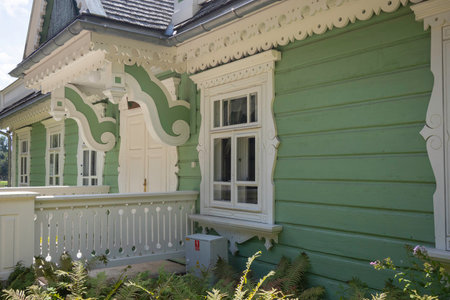 A green house with white trim and a white door. The house has a lot of windows and a porchの写真素材