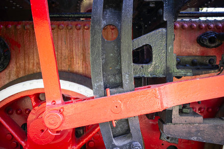 A red and black train engine with a red and black chain. The chain is attached to the engine. The image has a vintage feel to itの写真素材