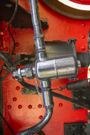 A black and silver pipe is attached to a red and white machine. The pipe is covered in a white substance, which could be rust or paint. The machine appears to be old and possibly in disrepairの写真素材