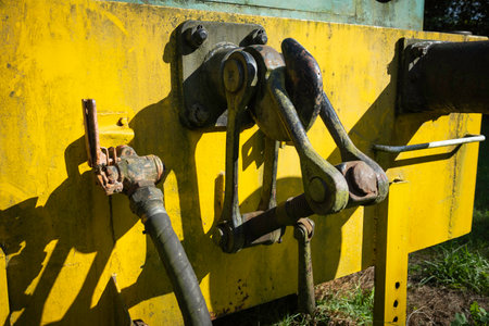 A yellow train car with a rusty bolt on the side. The bolt is missing and the train car is old