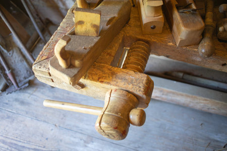 A wooden workbench with a hammer and a saw on it. The hammer is on the left side of the workbench and the saw is on the right sideの写真素材
