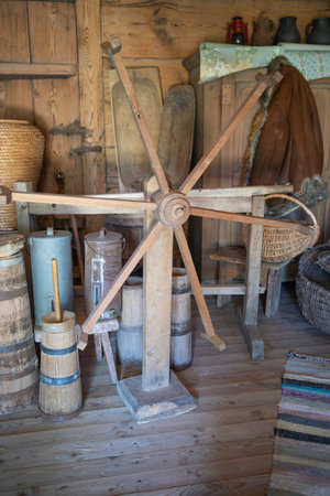 A wooden wheel is sitting in a room with other wooden objects. The room has a rustic, old-fashioned feel to itの写真素材